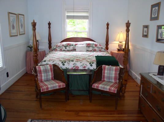 A bedroom with a four poster bed and two chairs