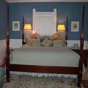 A bedroom with a large bed , two nightstands , a rug , and a chandelier.