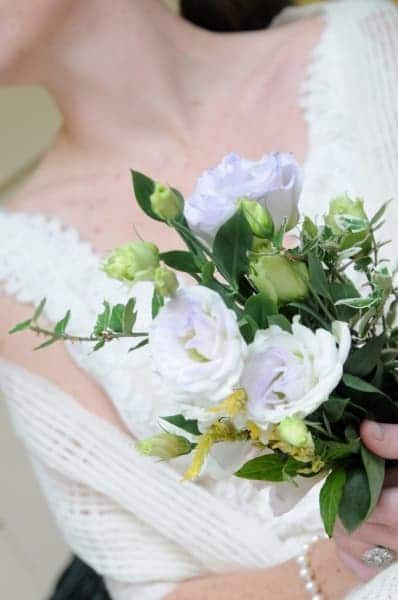 A woman in a white dress is holding a bouquet of white flowers