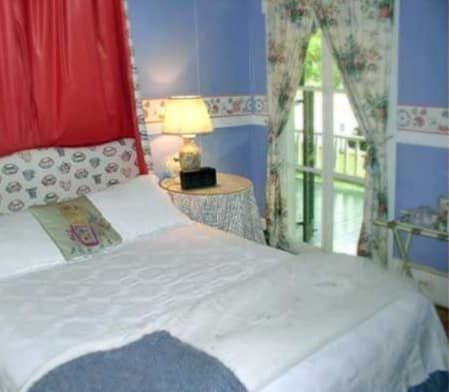 A bedroom with a bed , nightstand , lamp and window.