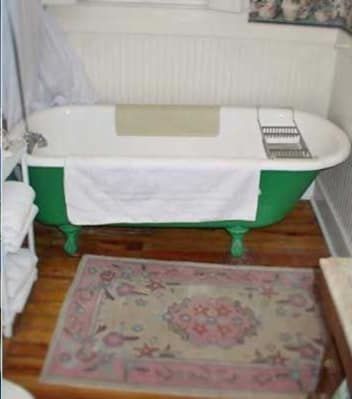 A green bathtub is sitting in a bathroom next to a rug.