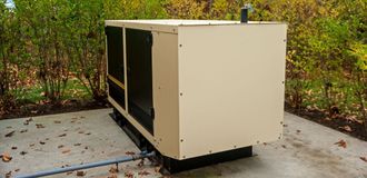 Large beige generator outdoors on concrete pad.