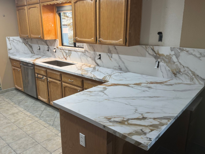 A kitchen with stainless steel appliances , white cabinets , and a large island with stools.