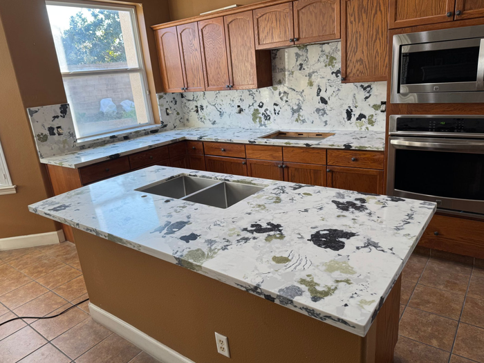 There is a marble counter top in the foreground and a bathroom in the background.