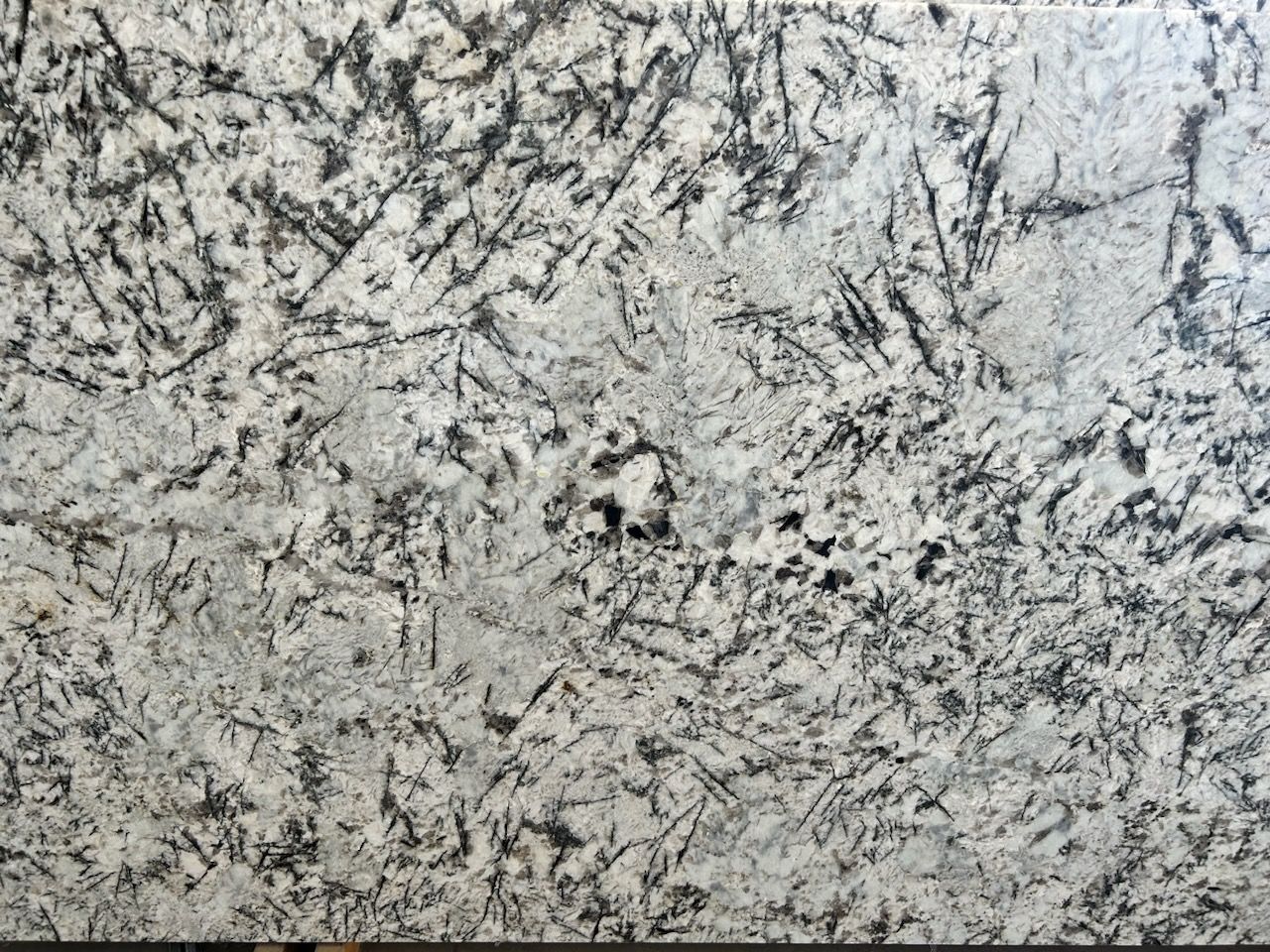 A close up of a white granite counter top with black spots.