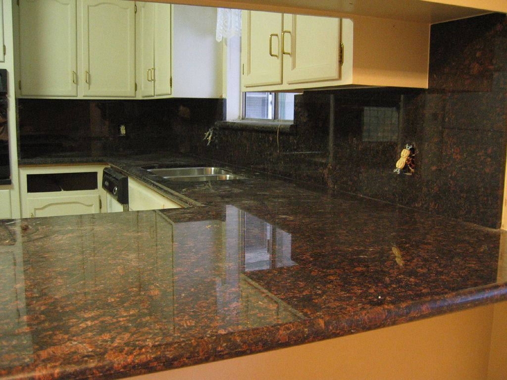 A kitchen with granite counter tops and white cabinets