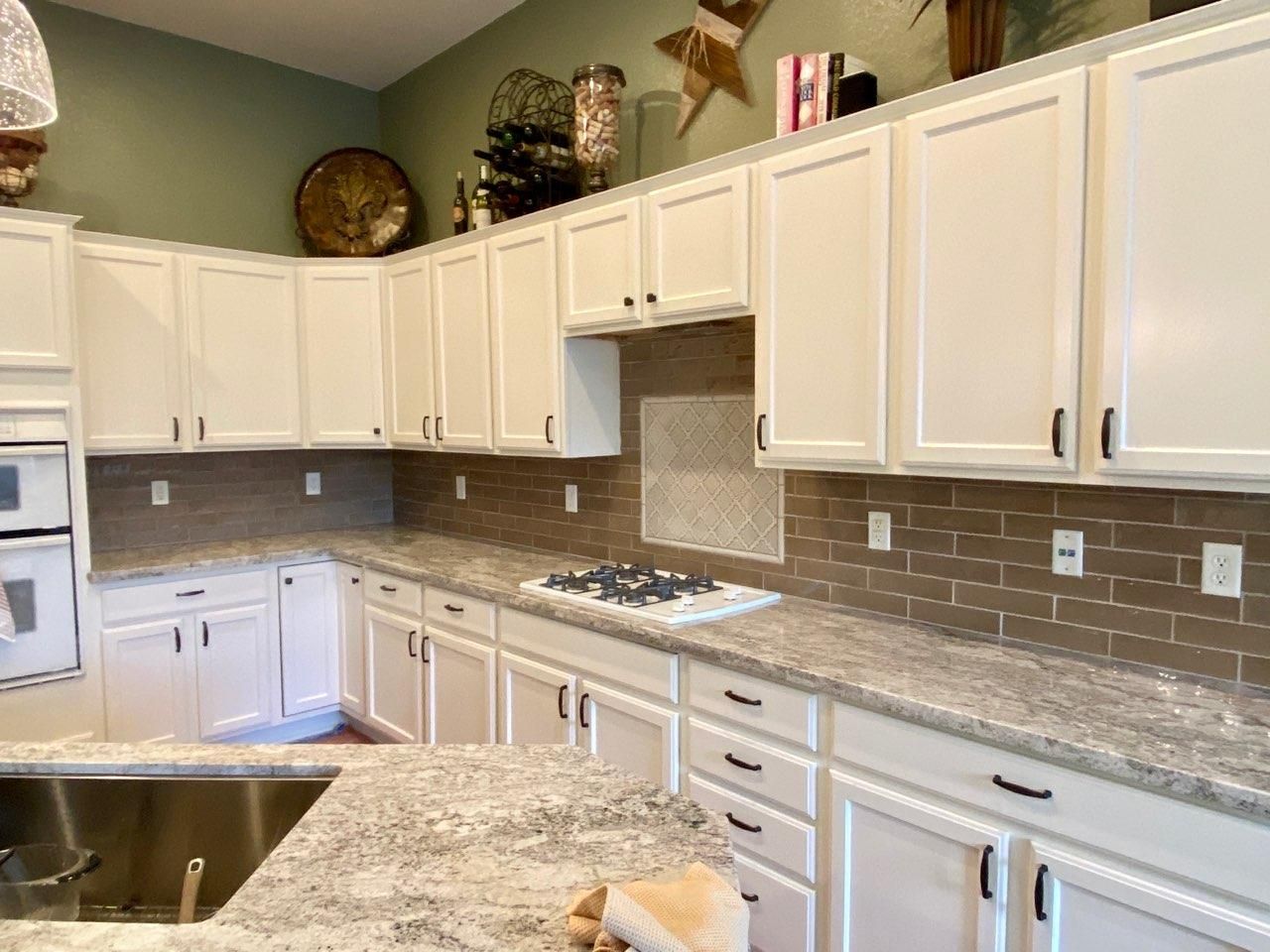 A kitchen with white cabinets and granite counter tops.