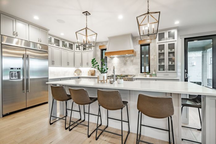 A kitchen with stainless steel appliances , white cabinets , and a large island with stools.