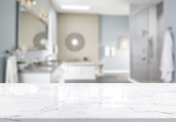 There is a marble counter top in the foreground and a bathroom in the background.