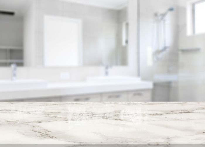 There is a marble counter top in the foreground and a bathroom in the background.