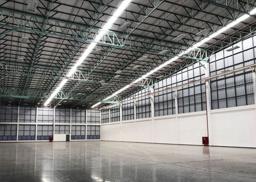 A large empty warehouse with lots of windows and lights on the ceiling.