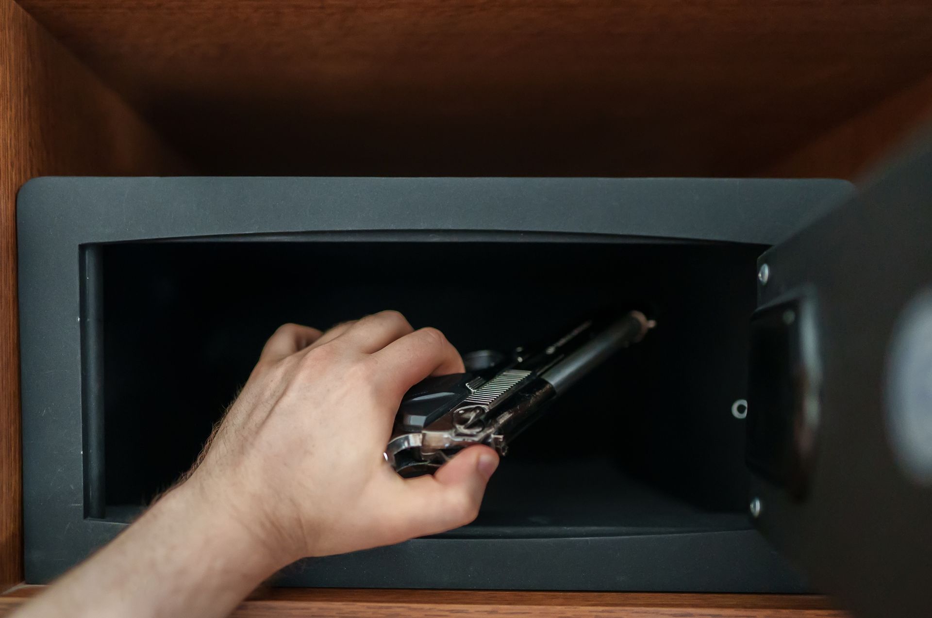 Man putting the weapon in a gun storage safe.