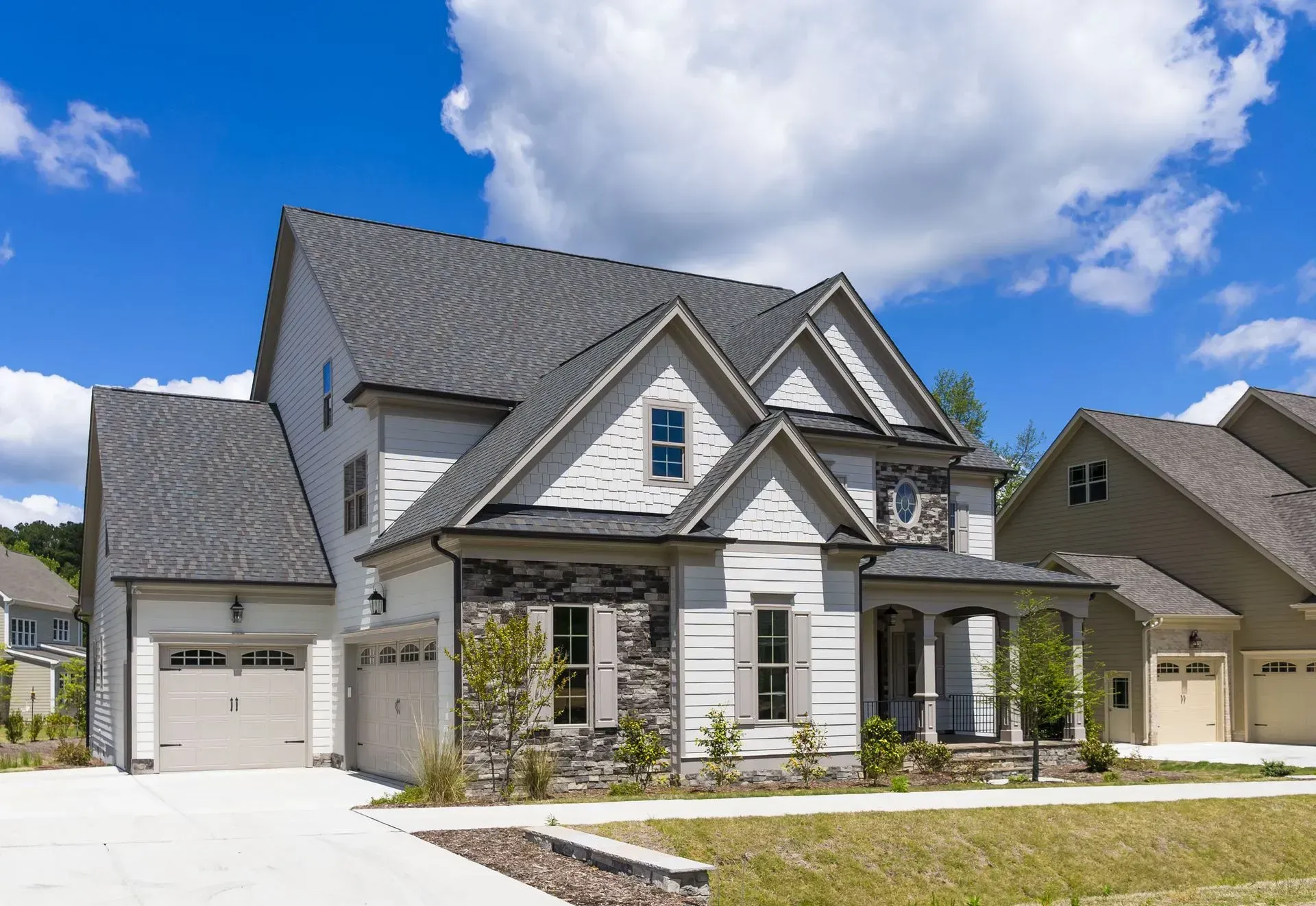 A large white house with a gray roof in a residential neighborhood.