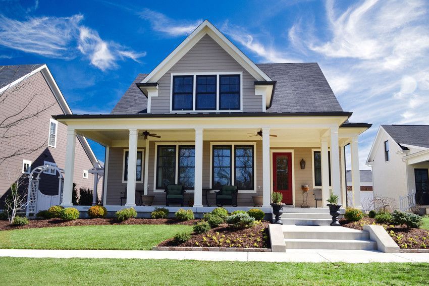 A house with a large porch and a red door