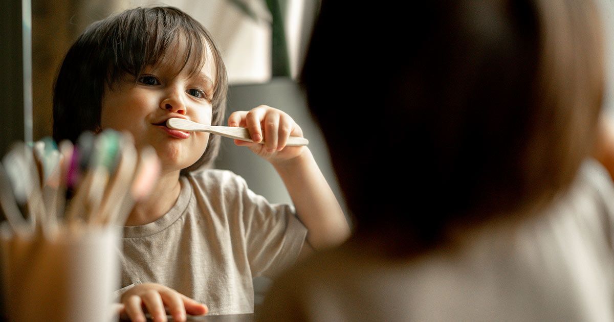 a young boy is brushing his teeth in front of a mirror .