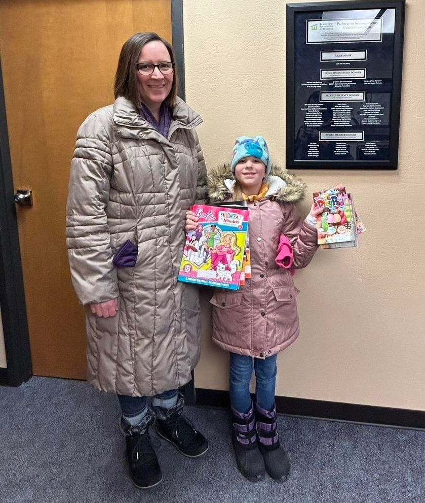 A woman and a little girl are standing next to each other in a hallway.