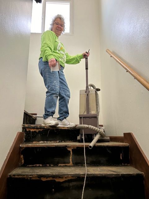 A woman is standing on a set of stairs holding a vacuum cleaner