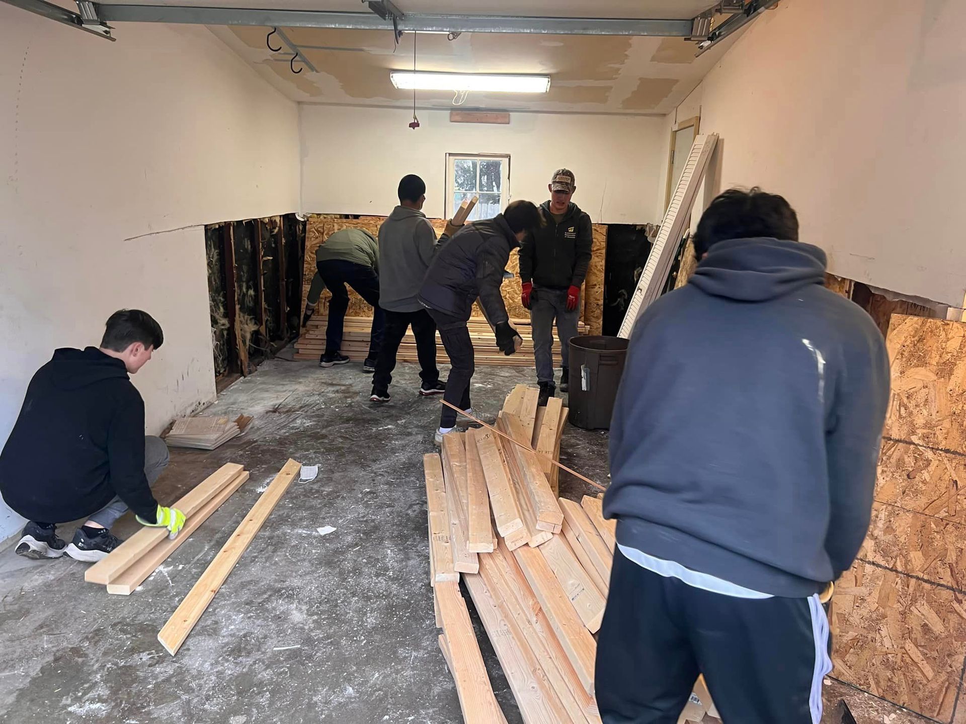 A group of men are working in a garage with wood.