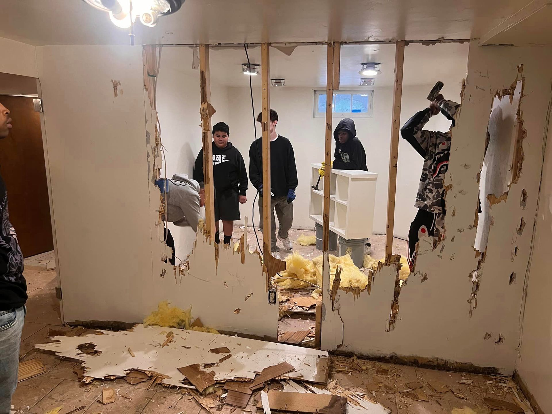 A group of people are standing in a room with a hole in the wall.