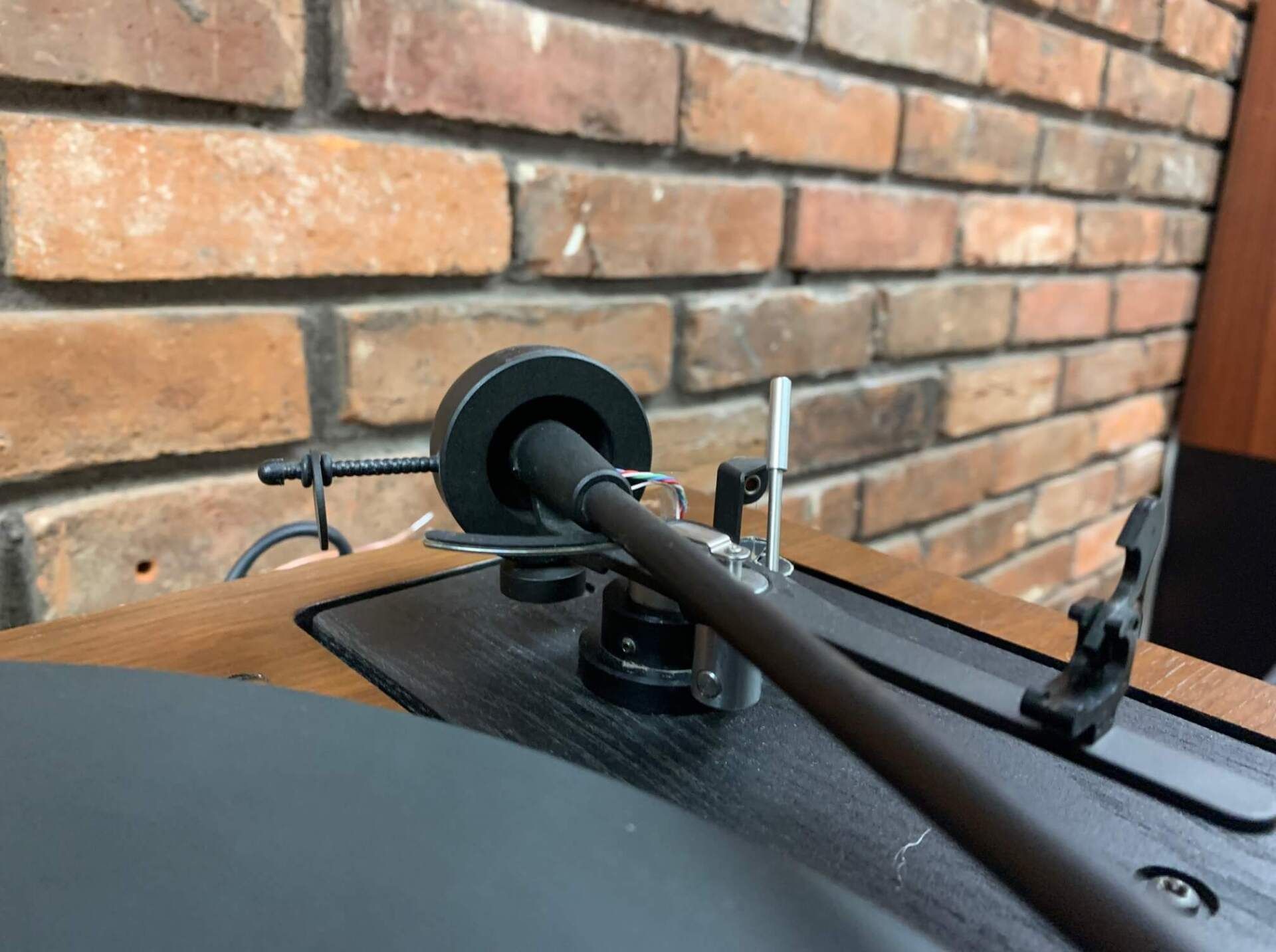 A record player is sitting in front of a brick wall.