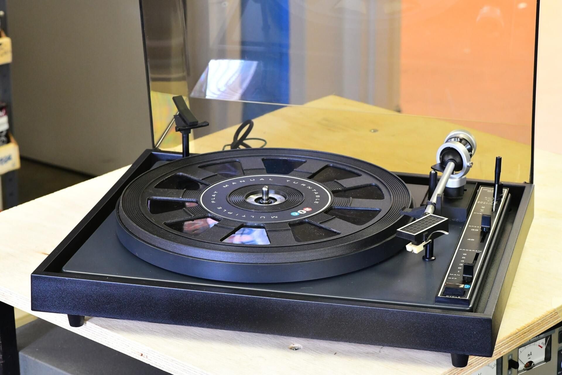 A record player is sitting on top of a wooden table.