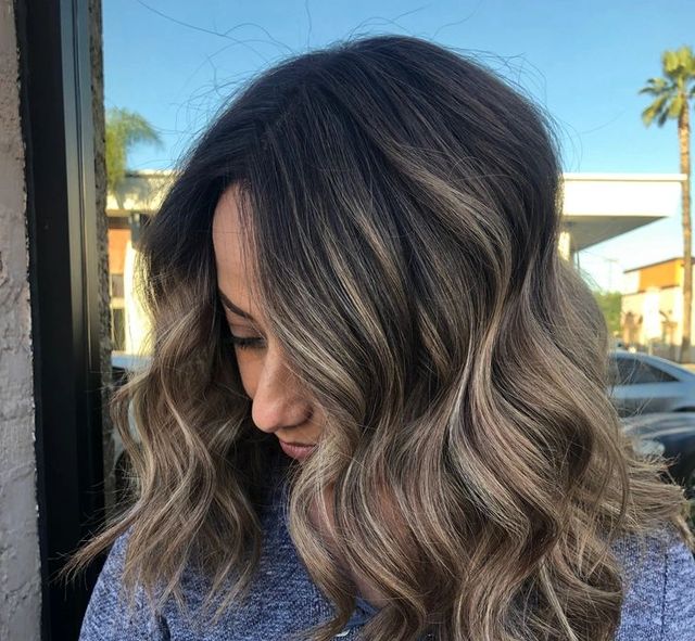 A woman with long wavy hair is wearing a blue shirt.