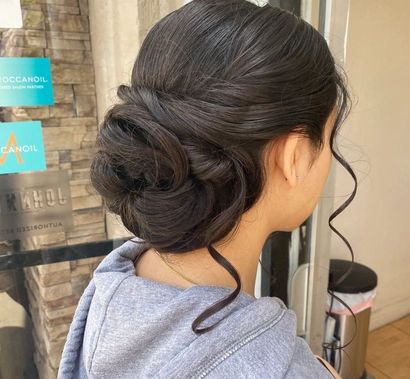 A woman with her hair in a bun is standing in front of a sign that says alcohol