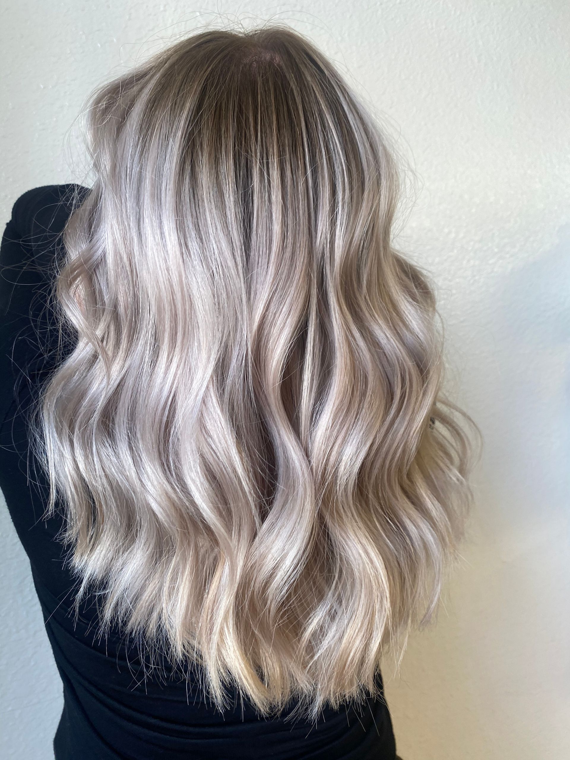 A woman with long blonde hair is wearing a black shirt.