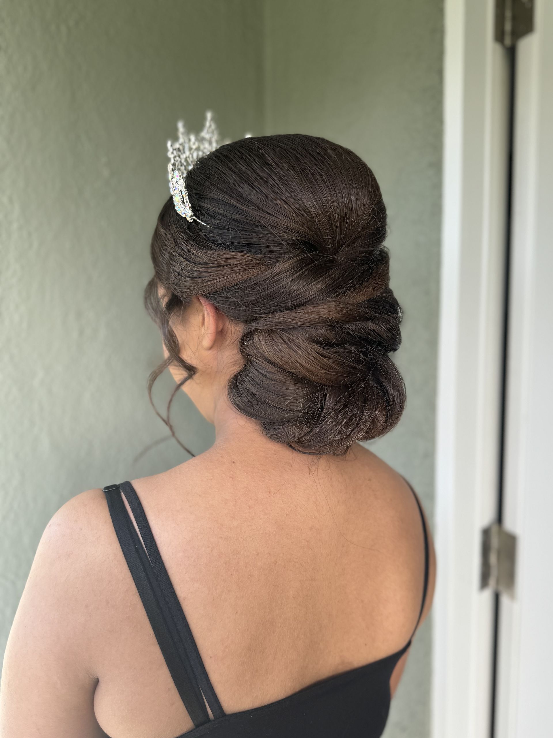 The back of a woman wearing a black dress and a tiara.