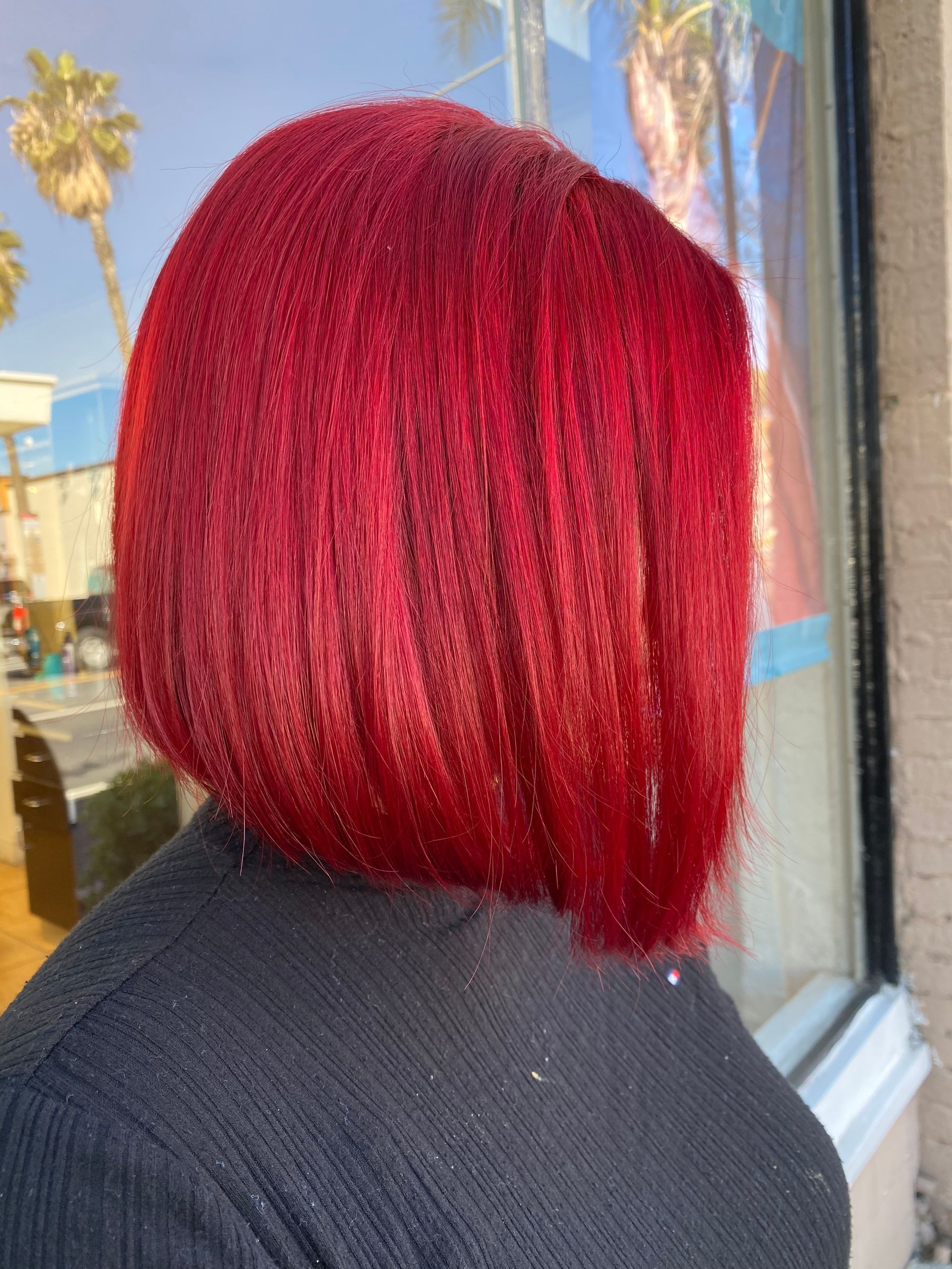 A woman with red hair is standing in front of a window.