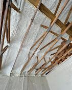 A room with a ceiling that is covered in foam and wooden beams.