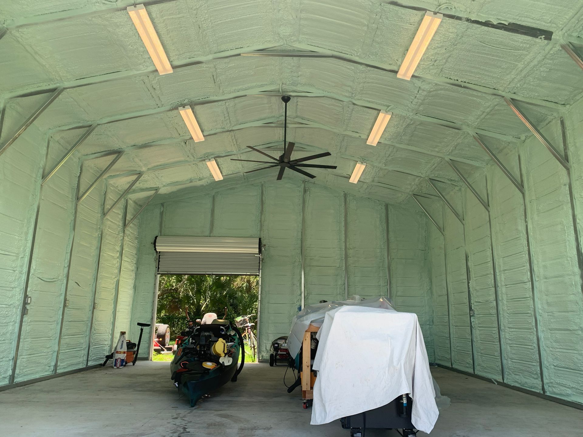 A motorcycle is parked inside of a garage with a ceiling fan.
