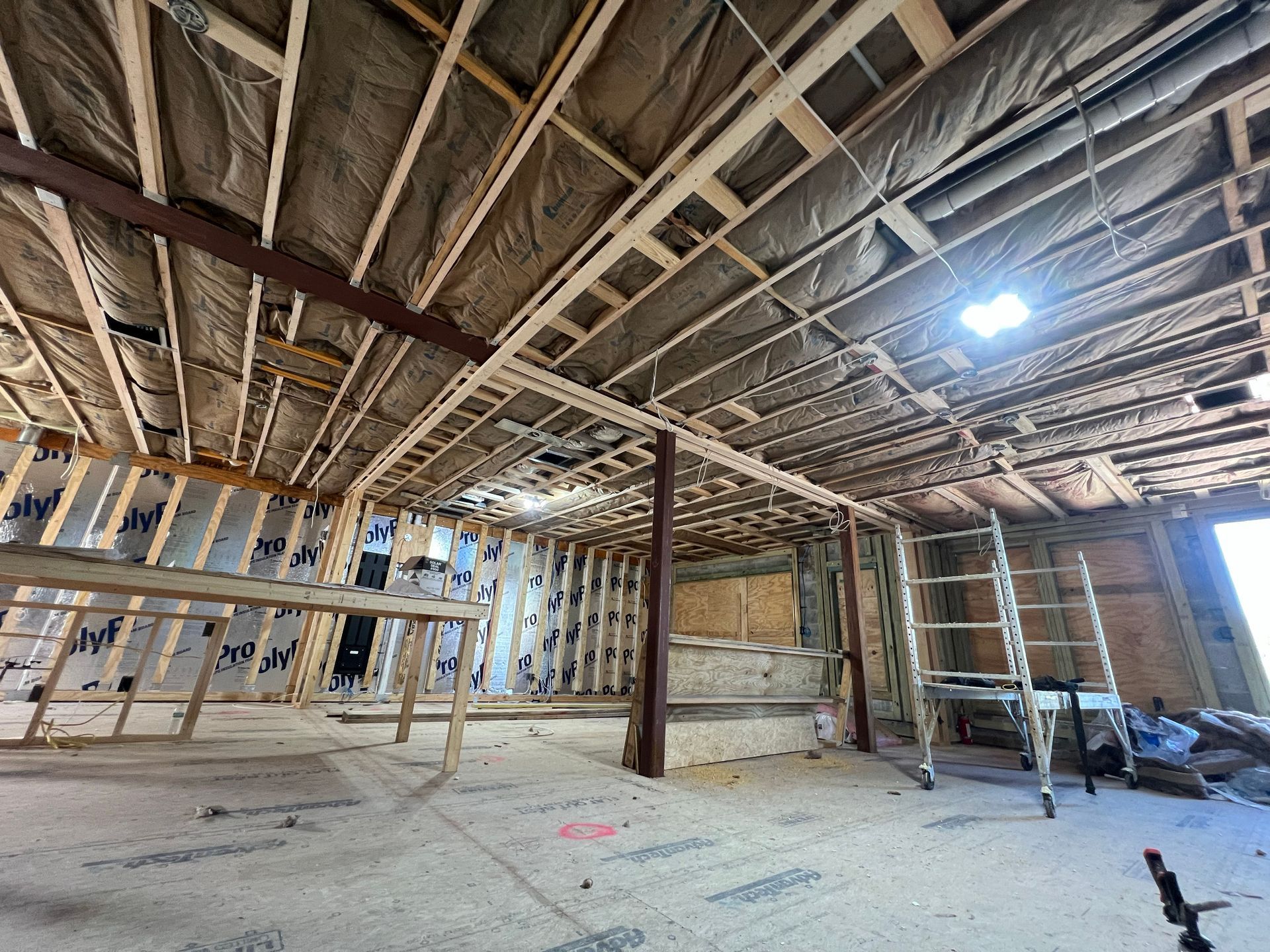 A large room with a lot of wooden beams and a ladder.