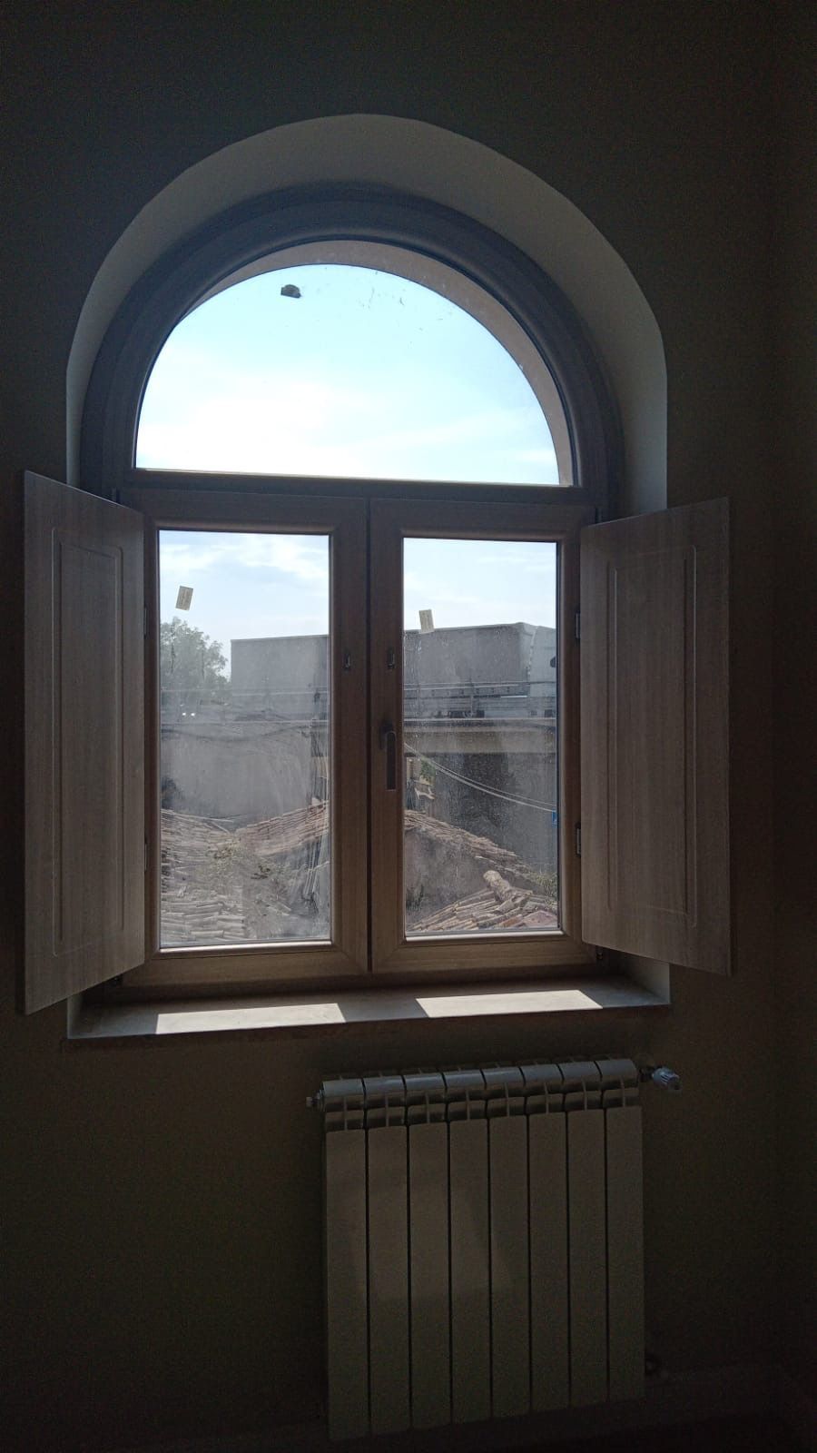 Primo piano del telaio di una finestra in legno con maniglia a leva argentata.