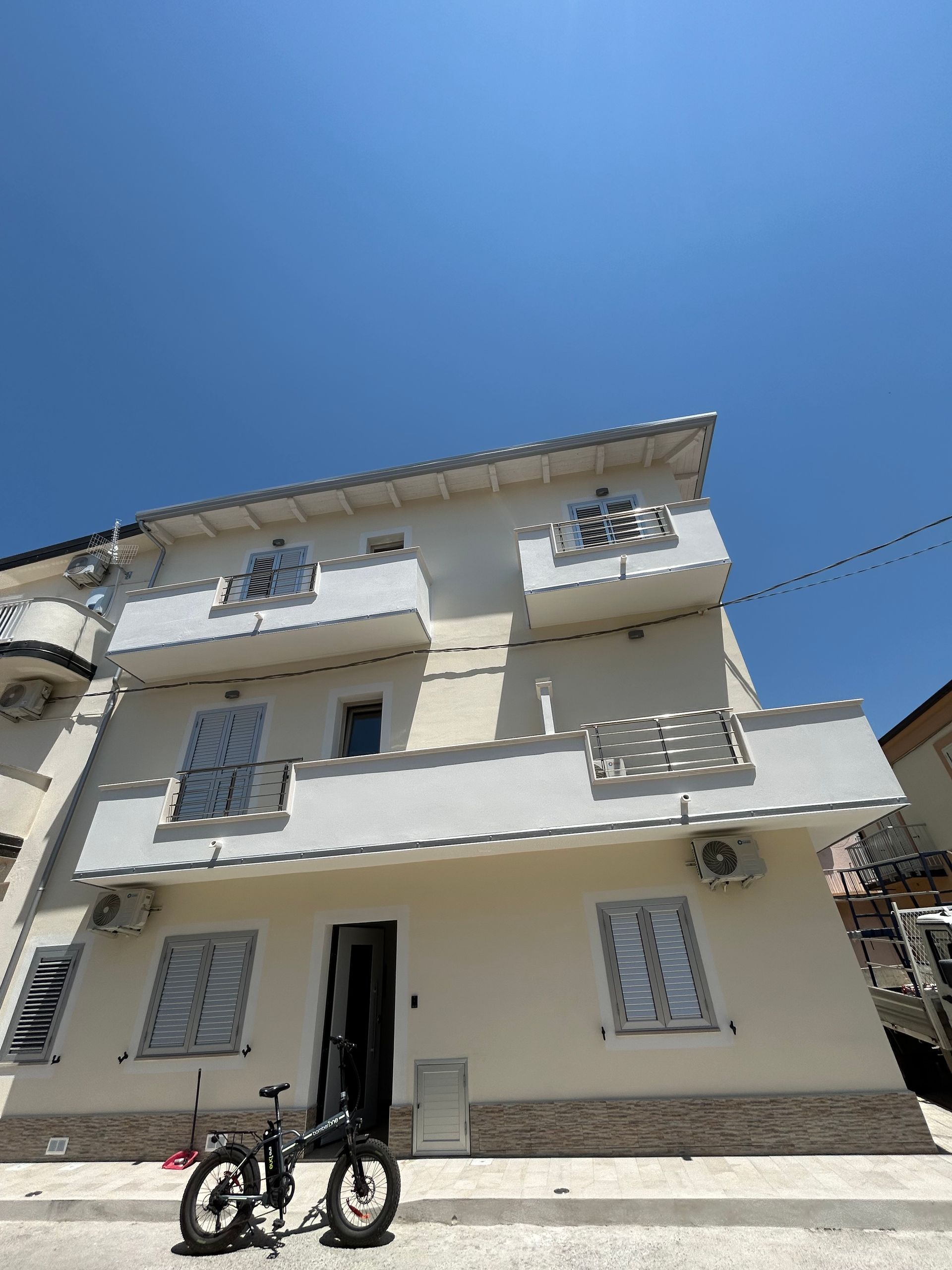 Mani con guanti blu installano una maniglia argentata su una porta bianca.