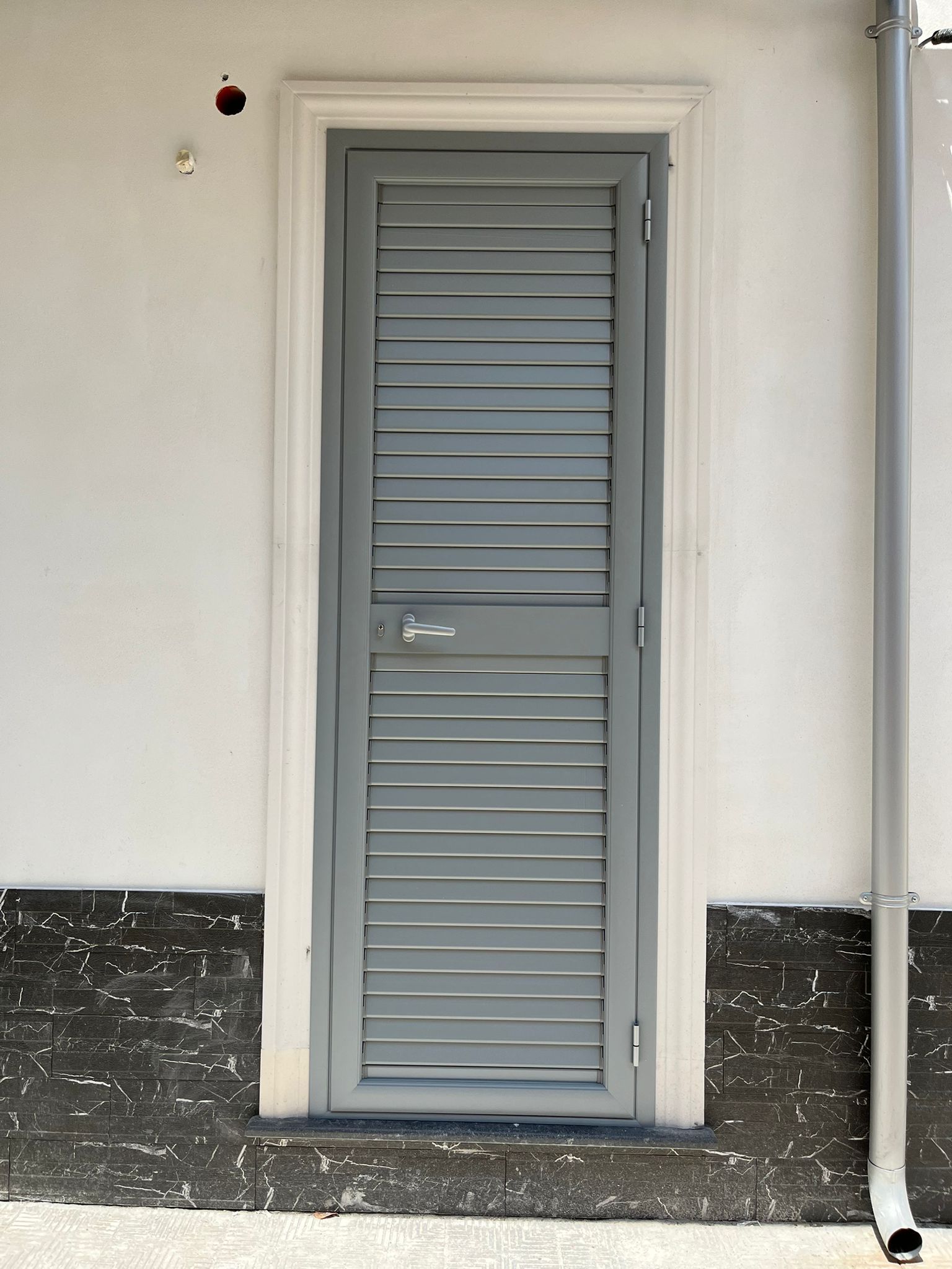 La luce del sole filtra attraverso una finestra, il cielo è luminoso. Infissi scuri e tende leggere.