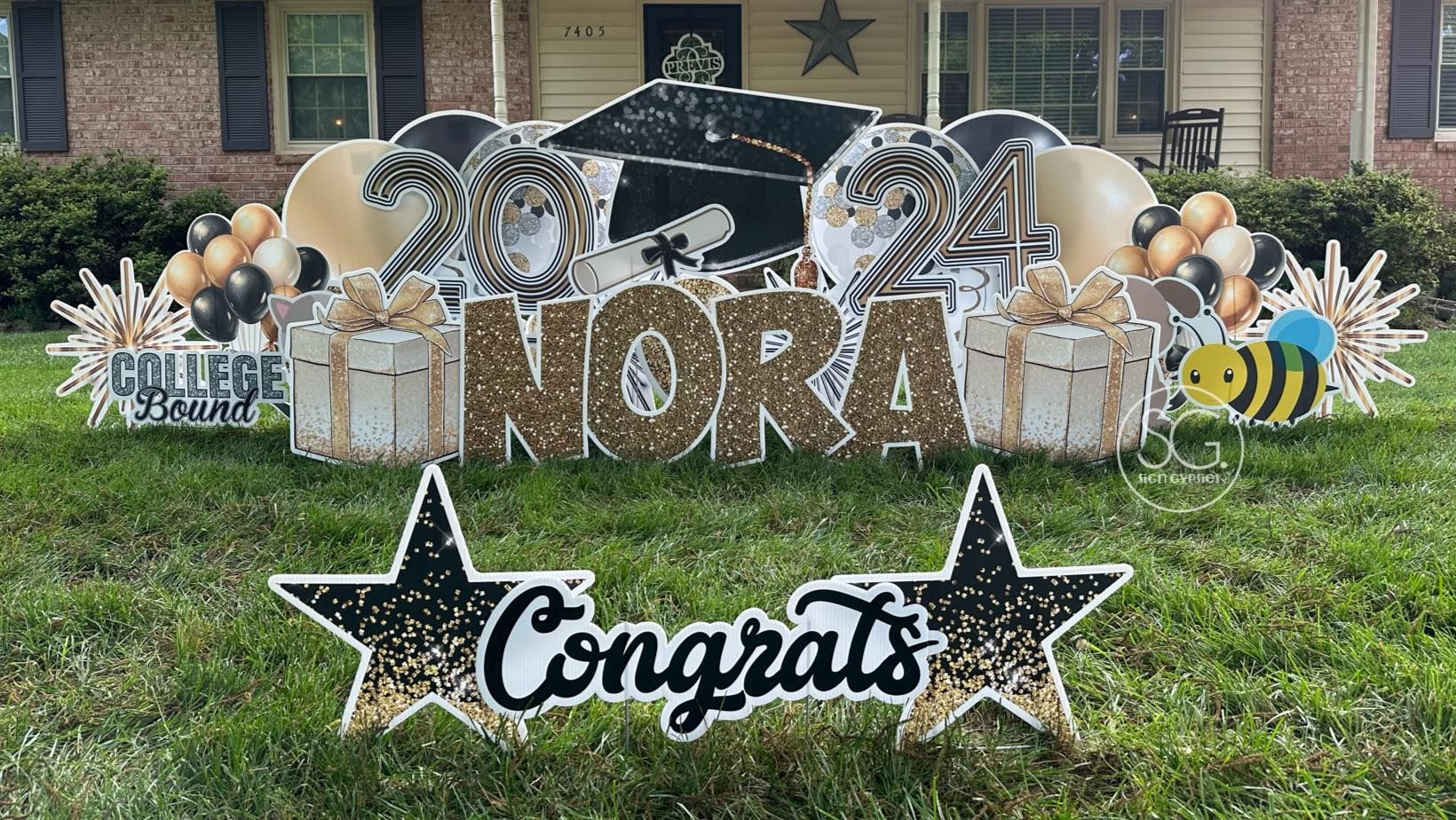 A congratulations sign is sitting in the grass in front of a house.