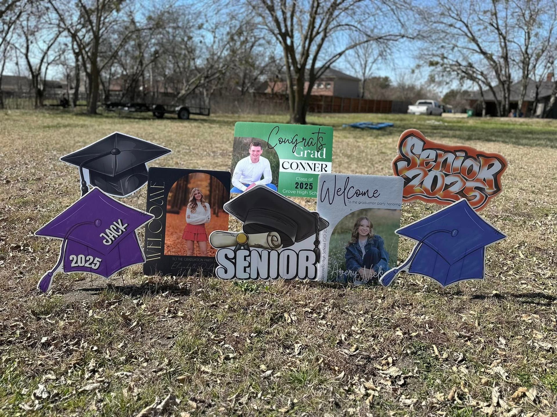 A group of graduation caps and signs are sitting in a field.