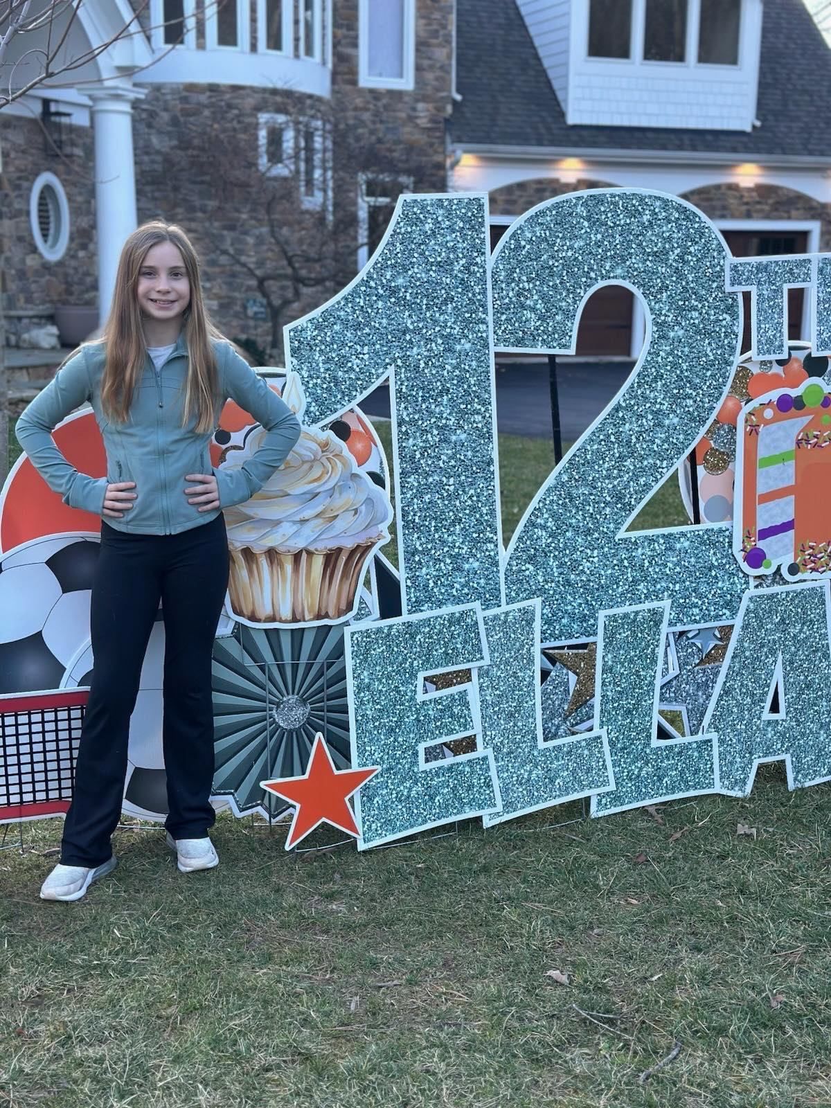 A young girl is standing in front of a 12th birthday sign.