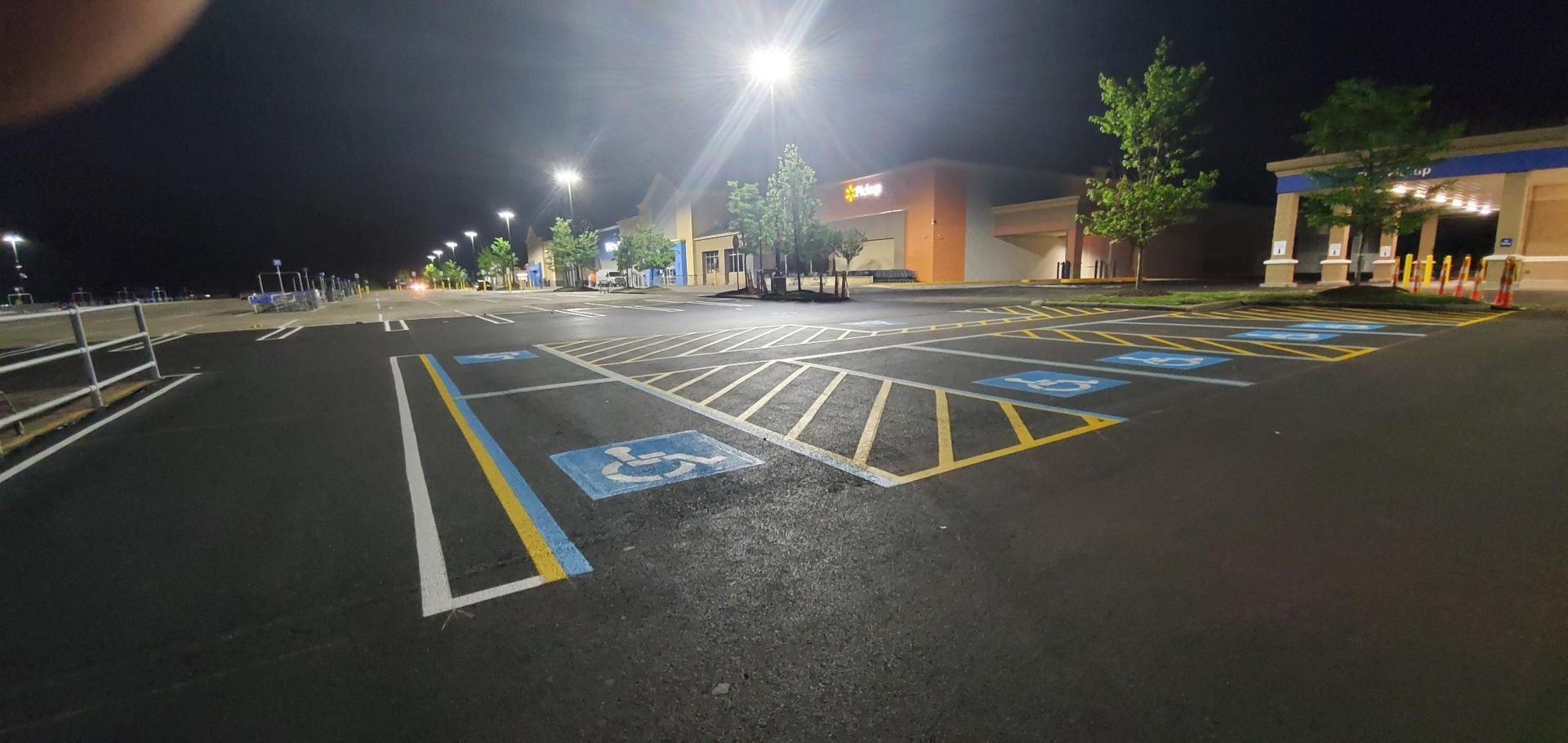 A parking lot is empty at night with a handicapped parking spot.