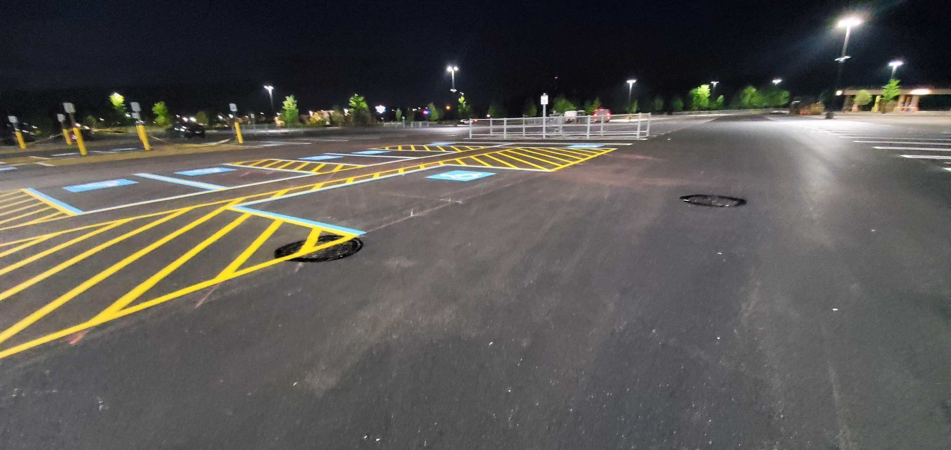 A parking lot is empty at night with a handicapped parking spot.