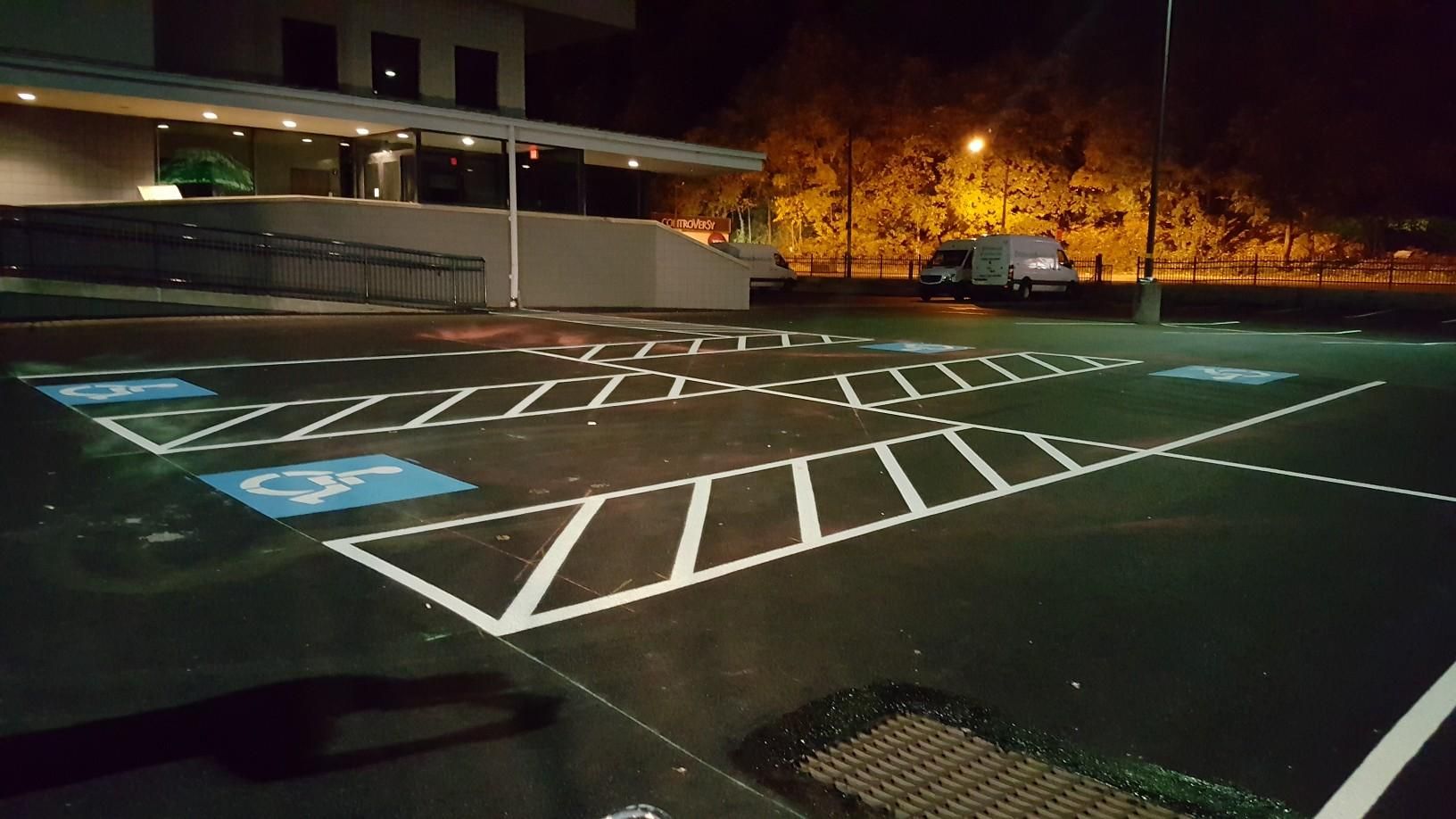 A parking lot at night with a handicapped parking spot