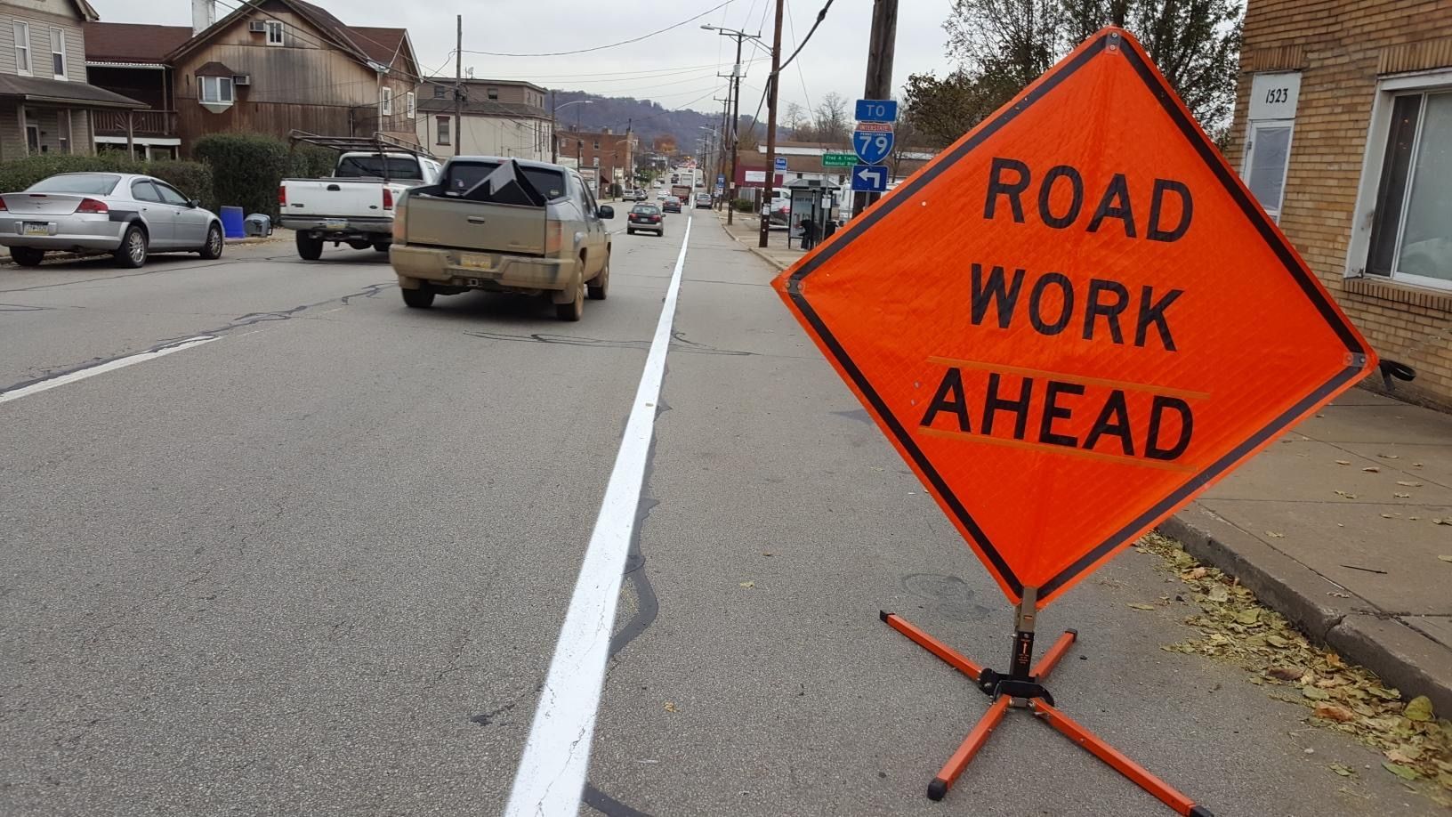 A road work sign is sitting on the side of the road.