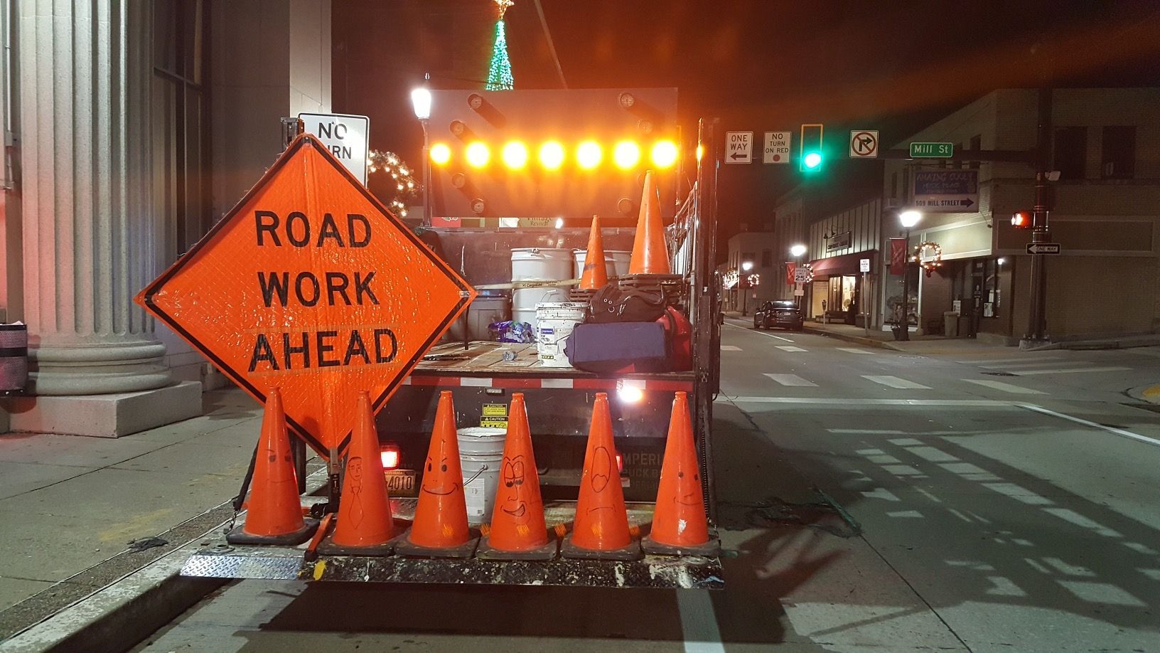 A truck is parked on the side of the road next to a sign that says road work ahead.