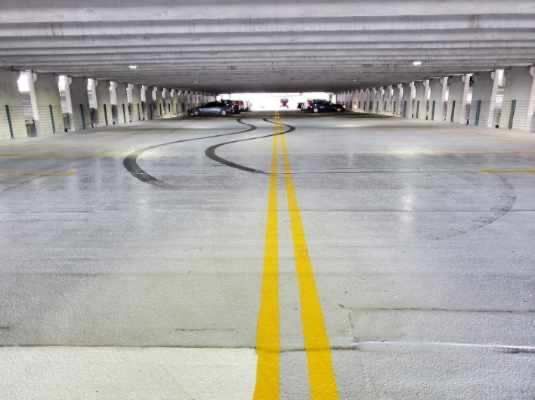 A parking garage with cars parked in it and a yellow line on the floor.
