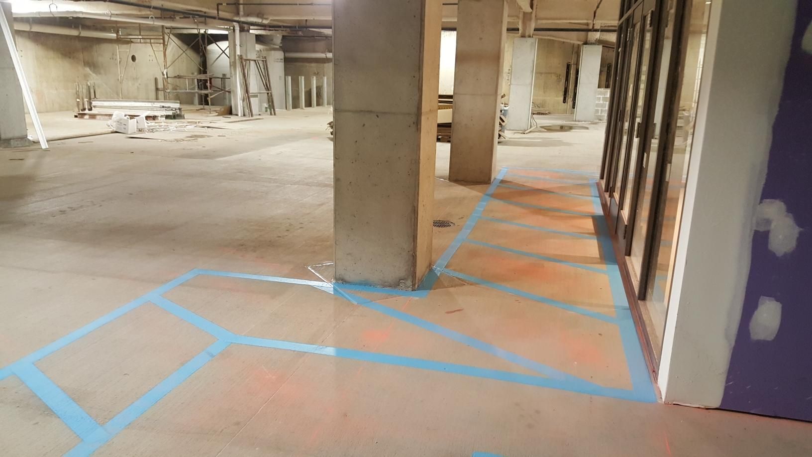 A large empty room with blue tape on the floor.