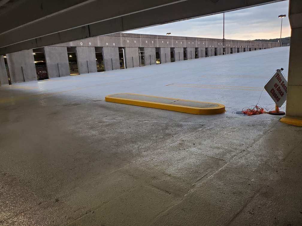 A parking garage with a yellow curb and a sign that says no parking