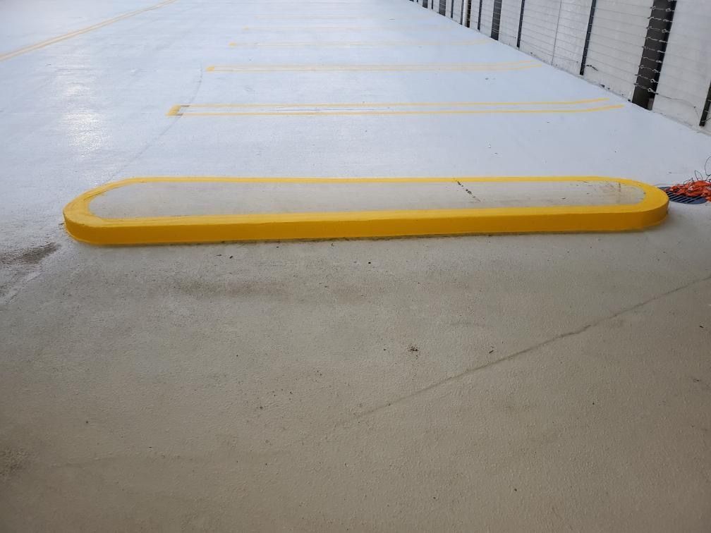 A yellow curb is sitting on the ground in a parking lot.