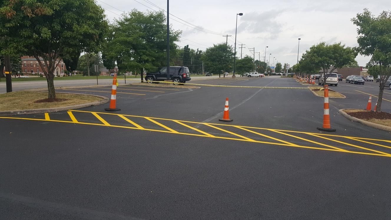 A parking lot with yellow lines and orange cones on the side of the road.