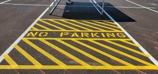 A no parking sign is painted on the ground in a parking lot.